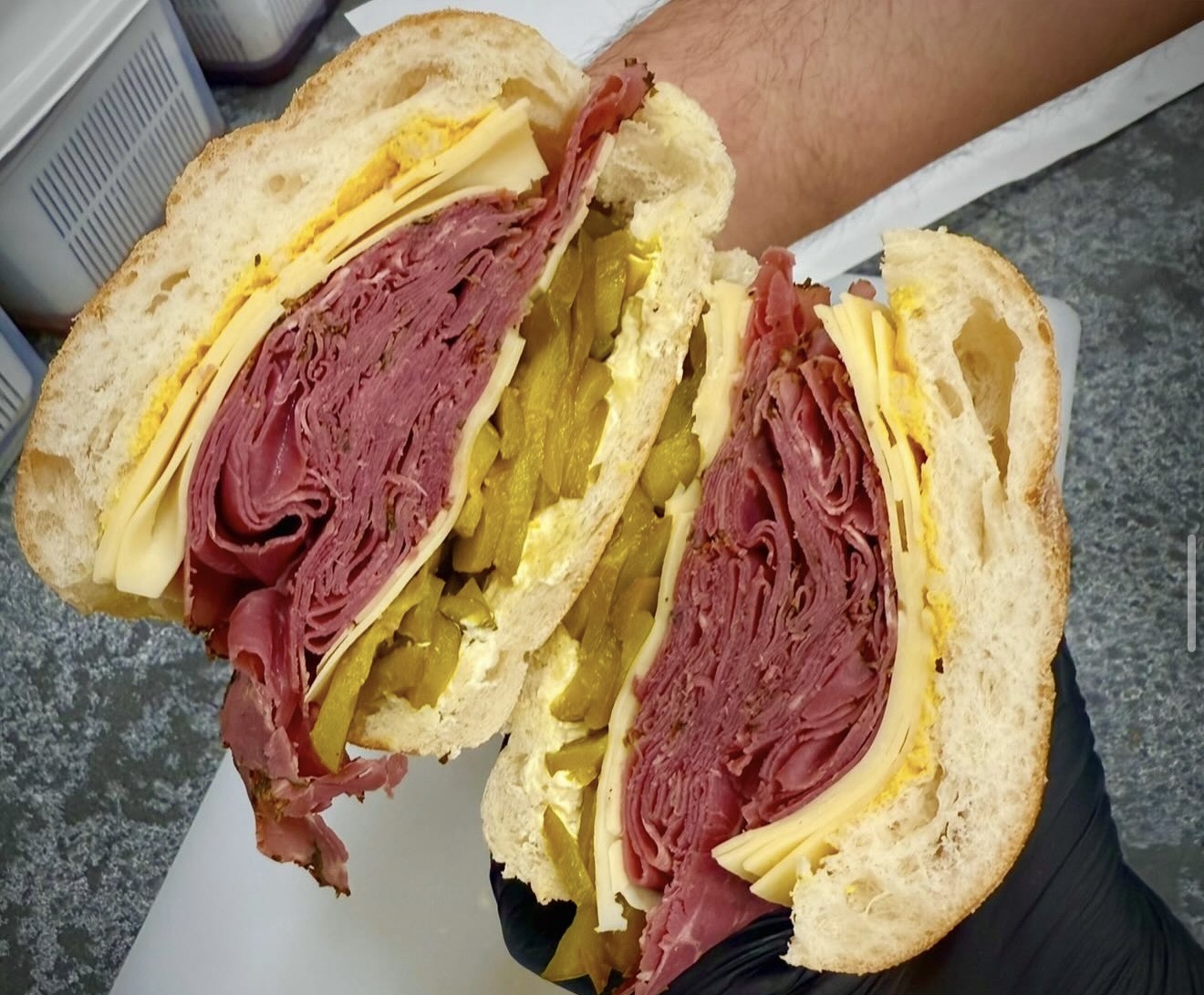 A generously stacked DeliCut sandwich with layers of meat, cheese and pickles